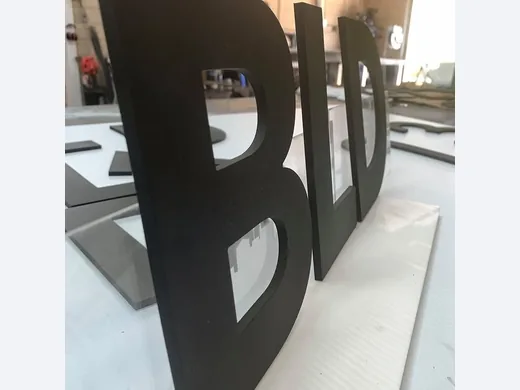 Side view of thick black dimensional sign letters showing routed edge depth