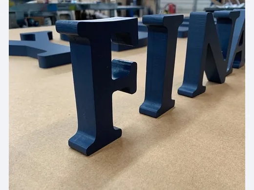 Blue dimensional sign letters standing upright during shop production